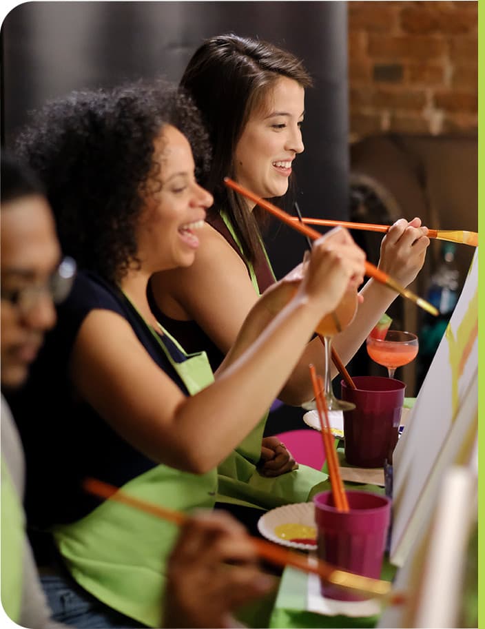 Friends celebrating at private paint and sip events with personalized art projects and party atmosphere